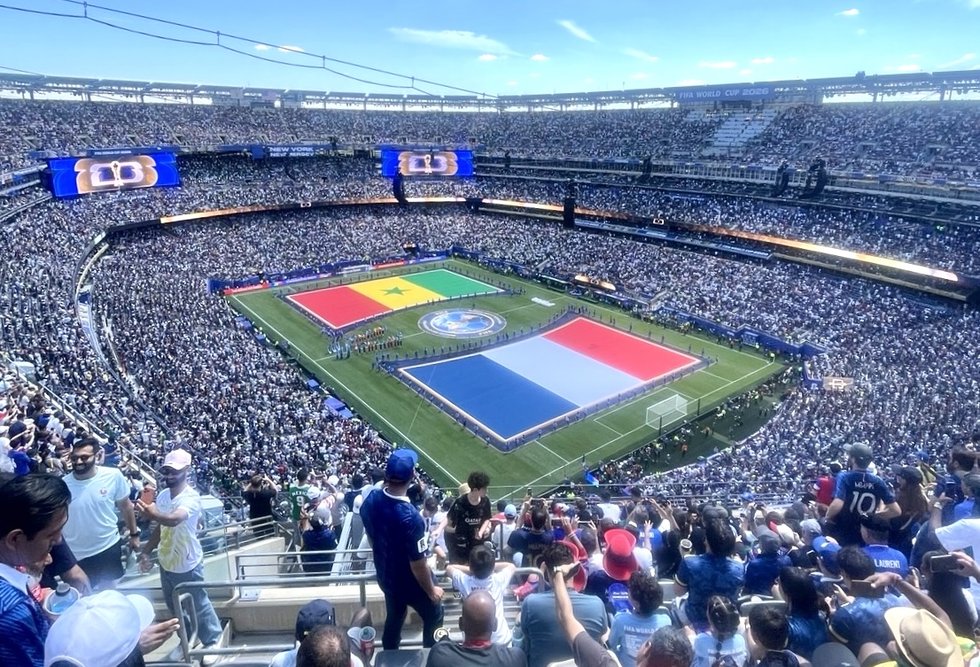 View from the stands at MetLife Stadium during France vs. Senegal at the FIFA World Cup 2026, with the French and Senegalese flags displayed on the pitch