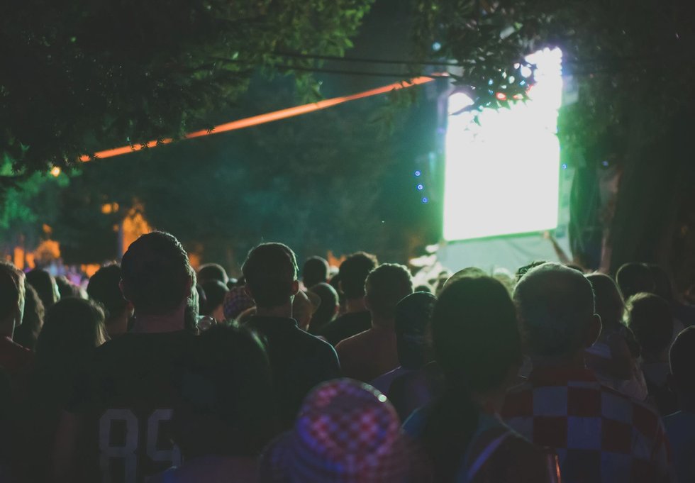 Crowd of people gathered to watch a large outdoor screen in the park