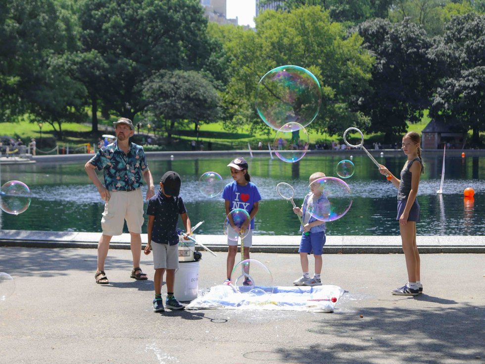 Kids making giant bubbles near Conservatory Water in Central Park with an adult nearby